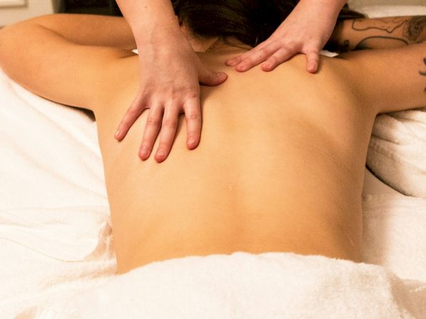 A person receives a relaxing back massage on a treatment table, with hands applying gentle pressure.