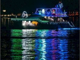 Boat with colorful holiday lights reflecting on the water